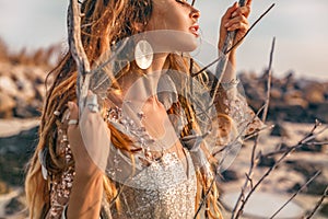 Close up portrait of beautiful young woman model with boho accessories outdoors at sunset