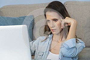 Close up portrait of a beautiful young woman smiling and looking at laptop screen