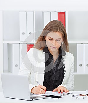 Close up portrait of a beautiful young woman smiling and looking at laptop screen.