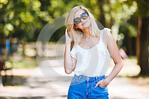 Close-up portrait of a beautiful young woman in sunglasses in a summer park.