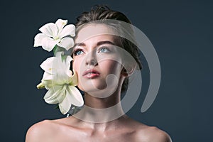 close-up portrait of beautiful young woman with white lilies looking away