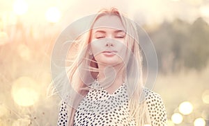 Close Up Portrait of beauty girl with fluttering white hair enjoying nature outdoors, on a field. Flying blonde hair on the wind