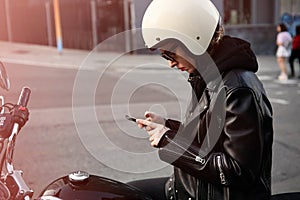 Close-up portrait of biker girl checking her smartphone and wearing white helmet.