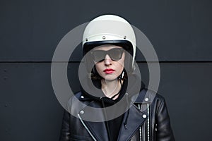 Close-up portrait of biker girl wearing sunglasses and white helmet. Black background.