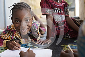 Close up Portrait of Black African Schoogirl Smiling and drawing on paper