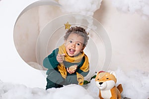 Close-up portrait of a black boy`s face, afro-american. The little black boy sits and smiles. Cute baby, baby in the game. Pretty