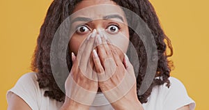 Close up portrait of black woman covering mouth in disbelief