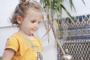 Close-up portrait of a blonde toddler girl with downcast eyes