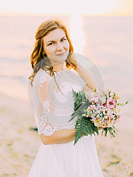 The close-up portrait of the bride holding the bouquet. The sunset composition.