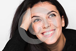 Close up portrait of brunette cheerful woman with healthy toothy smile with hand on hair.