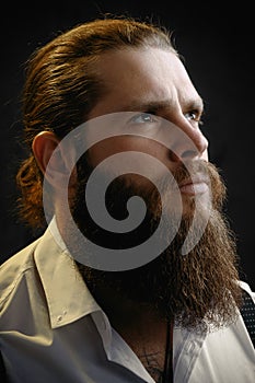 Close-up portrait of a brutal man with a beard and long hair he looks up