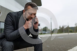 close-up portrait of a business man with a phone in his hands while talking with a thoughtful expression