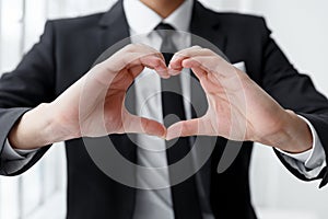 Close up of portrait of businessman making a heart with his hands.