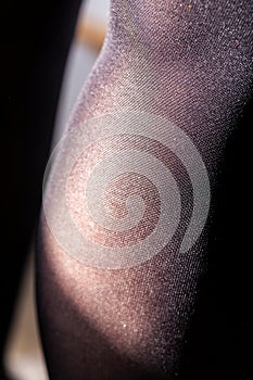 A close up portrait of a calf and popliteal part of a female leg in black nylon pantyhose or stockings. You can see the details in photo