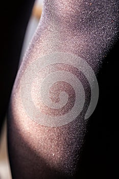 A close up portrait of a calf and popliteal part of a female leg in black nylon stockings or pantyhose. You can see the details in