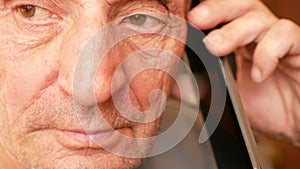 Close up portrait of caucasian elderly man listening attentively to the interlocutor on the phone. Parts of the face of an elderly