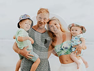 Close up portrait of Caucasian family spending time on the beach. Father and mother holding sons. Cute baby boys. Smiling parents