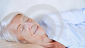 Close up portrait of caucasian happy calm elderly woman sleeping or relax on comfortable sofa at home. taking nap or