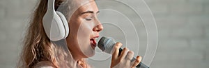 Close-up portrait of a caucasian woman with curly hair singing into a microphone. Beautiful sensual girl in white