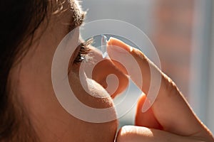 Close-up portrait caucasian woman putting on a contact lens.