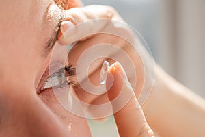 Close-up portrait caucasian woman putting on a contact lens.