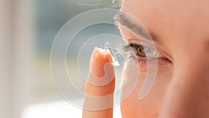 Close-up portrait caucasian woman putting on a contact lens.