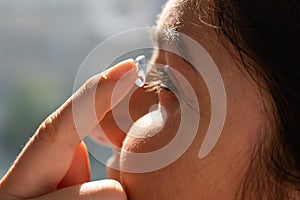 Close-up portrait caucasian woman putting on a contact lens.