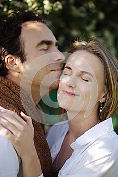 Close-up portrait of a Caucasian young loving couple embracing. Sunset scene. Flowering on background. Love and