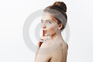 Close up portrait of charming beautiful young european woman with dark long hair in bun hairstyle and naked skin