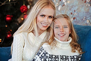 Close-up portrait of charming blonde mother and daughter sitting