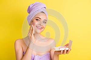 Close-up portrait of charming cheery girl wiping oily skin with napkin isolated over vibrant yellow color background photo