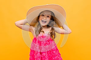 Close up portrait of a charming cute young girl with a straw hat on a yellow background