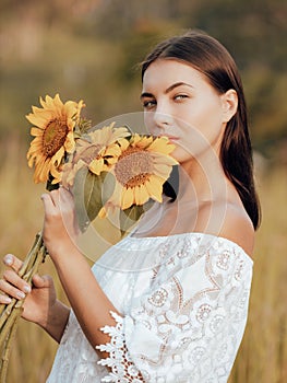 Close up portrait of charming woman holding sunflowers. Nature and outdoor concept. Summer. Beautiful face. Sunset time