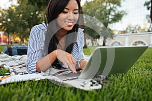 Close-up portrait of cheerful asian student, typing on laptop, o