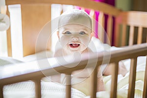 Close-up portrait of a cheerful cute baby in the crib at home