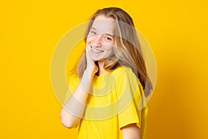 Portrait of a cheerful girl. Happy smiling teenage girl on a yellow background