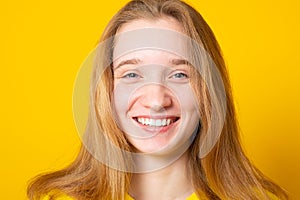 Close-up portrait of a cheerful girl. Studio portrait of a smiling teenage girl on a yellow background