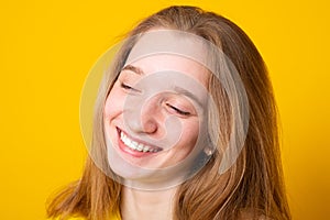 Close-up portrait of a cheerful girl. Studio portrait of a smiling teenage girl on a yellow background