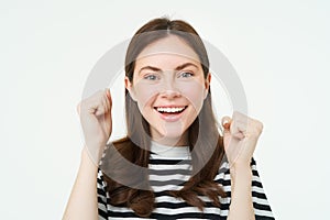 Close up portrait of cheerful woman, raising hands up and smiling, celebrating success, achievement or goal, rooting for