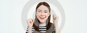 Close up portrait of cheerful woman, raising hands up and smiling, celebrating success, achievement or goal, rooting for