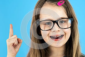 Close up portrait of a child school girl wearing looking glasses holding up point finger in I have an idea gesture isolated on