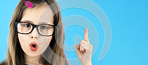 Close up portrait of a child school girl wearing looking glasses holding up point finger in I have an idea gesture isolated on