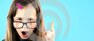 Close up portrait of a child school girl wearing looking glasses holding up point finger in I have an idea gesture isolated on