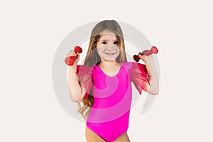 Close-up portrait, child, smiling, funny looking, happy little girl wearing pink gymnastics leotard, lifting dumbbells