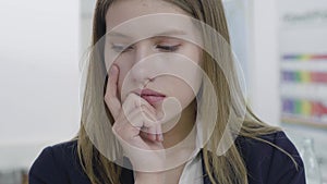 Close up portrait of concerned sad young lady in formal clothes looking away and in the camera, thinking about her