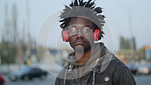 Close-up portrait of confident handsome African American man in eyeglasses turning on headphones and dancing to music