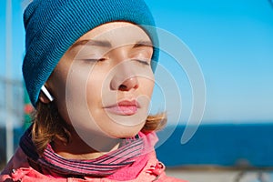 Close up portrait of confident woman at seaside listening to music in earphones