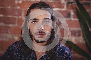 Close up portrait of confident young male photographer against brick wall