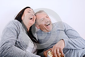 Portrait of couple laughing watching television and eating pop c