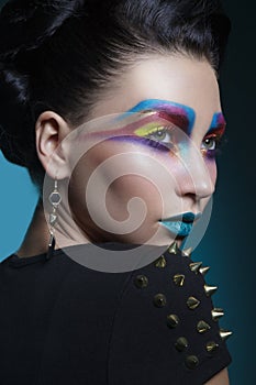 Close-up portrait of a creative and colored artistic make-up, with blue lips, isolated dark blue background.